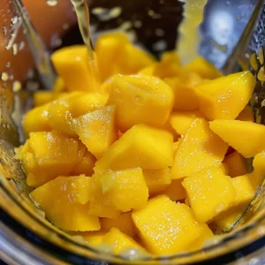 Blending fresh mangoes with simple syrup and lemon juice for mango sorbet