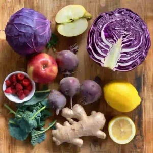 Fresh purple cabbage, beet, berries, apple, lemon, and ginger on kitchen counter