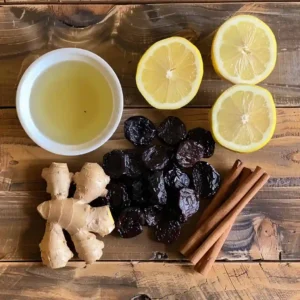 Organic pitted prunes, lemon, ginger, and cinnamon displayed on a wooden board