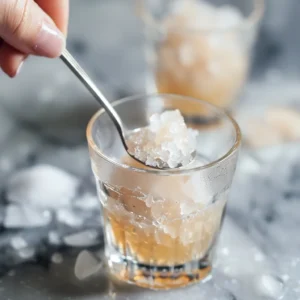 Adding a pinch of pink Himalayan salt to a glass of ice water – step in making the salt and ice trick