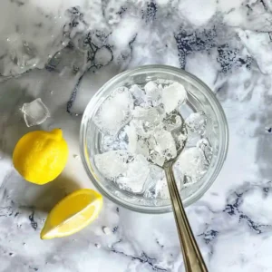 Sprinkling Himalayan pink salt into iced water with lemon in background