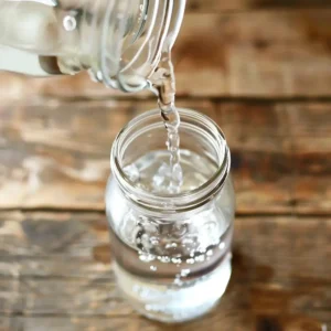 Stirring the pink salt and water mixture in a glass jar to create sole water