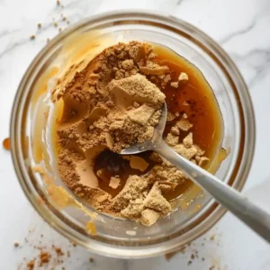 Stirring cinnamon, honey, and brown sugar in a glass cup for latte