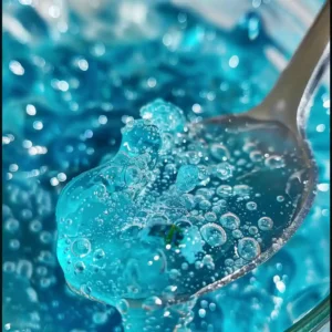 Blue gelatin portion on a small plate with spoon, lemon zest and mint – serving suggestion